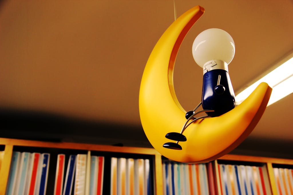 Serlig Artistic depiction of a light bulb seated on a crescent moon amidst bookshelves.
