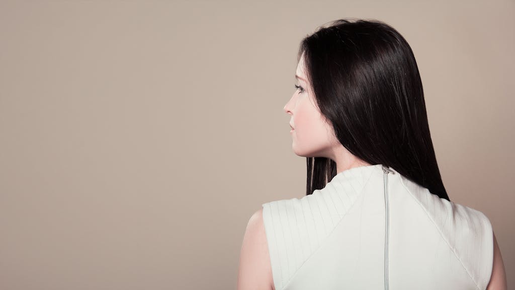 Serlig Profile view of a brunette woman in white attire indoors on a neutral background.