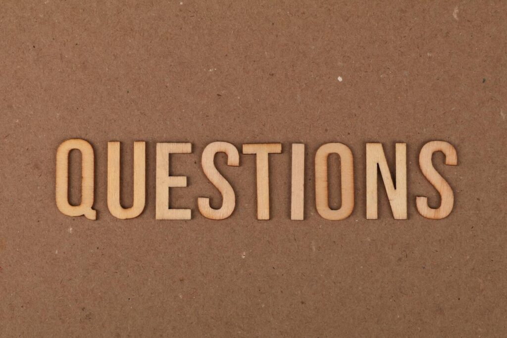 Lufanest spelling the word "QUESTIONS" on a cardboard background, providing a neutral copyspace.