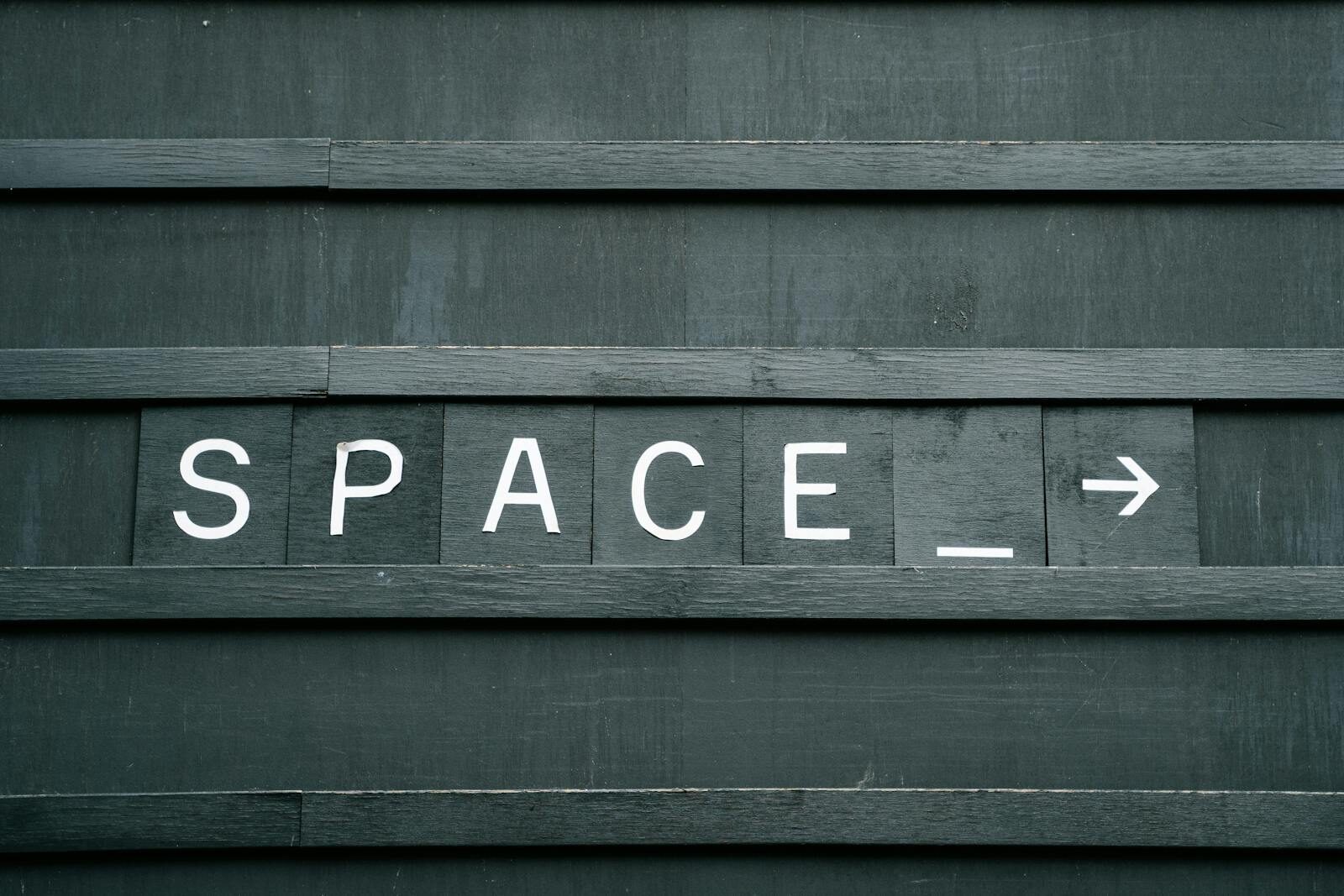 Dolfier Close-up of a minimalist wooden sign with 'SPACE' in capital letters and an arrow, creating a conceptual theme.