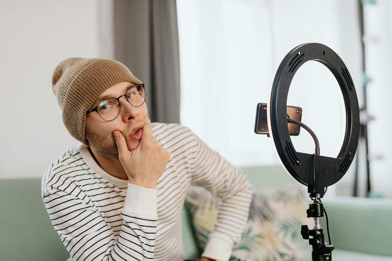 Sixmagazine Young content creator with beanie and glasses posing in front of ring light indoors.
