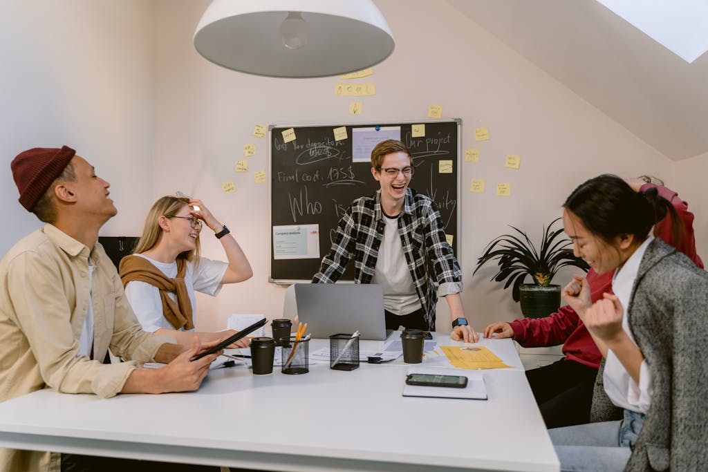 Kongotech Org A cheerful and diverse team engages in a lively brainstorming session in a modern office environment.