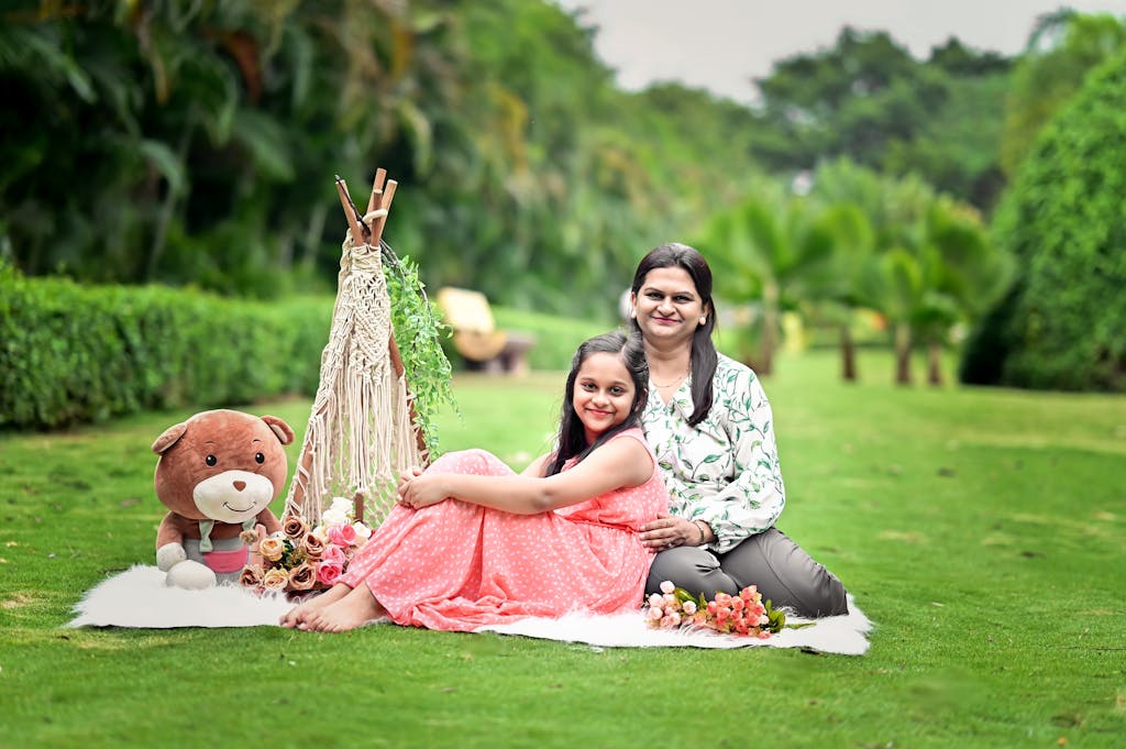 Bolly4u Me A joyful mother and daughter enjoy a picnic setting in a vibrant green garden.