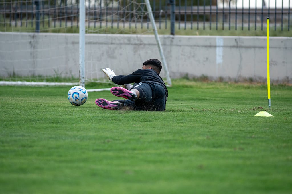 Wynonna Judd Performance Reactions A soccer goalkeeper dives to save the ball during practice on a grassy field.