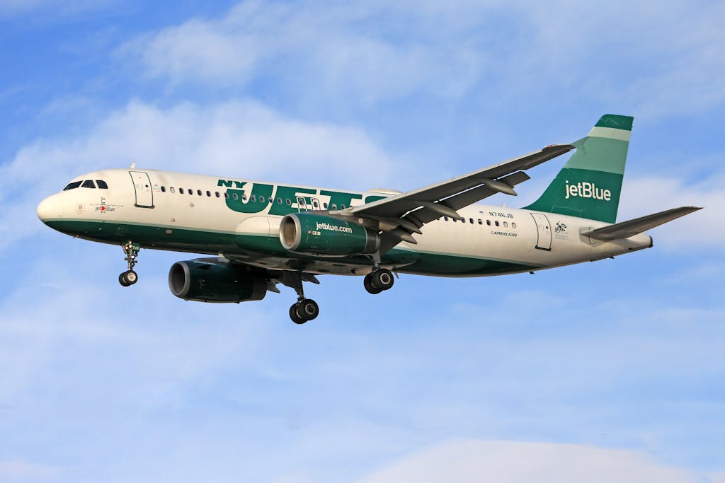 Jets vs Bengals JetBlue Airbus A320 in flight with NY Jets livery against a clear blue sky.