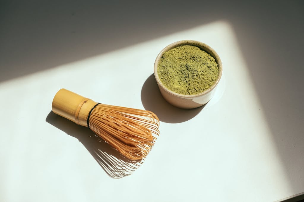 Bin Matcha Minimalist composition featuring matcha powder and bamboo whisk in sunlight.