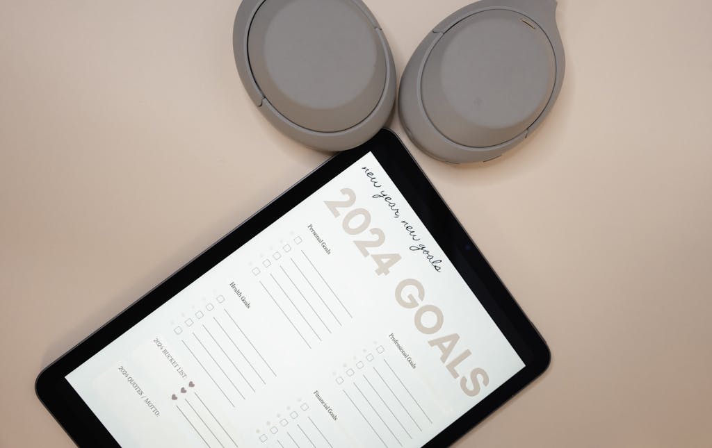 Kongotech Org Tablet displaying 2024 goals on a peach background with headphones, highlighting organization and planning.