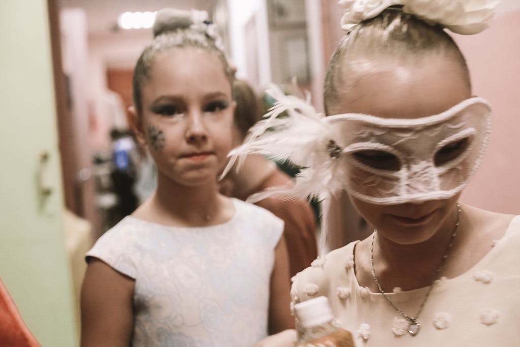 SocialMediaGirls Forum Two young girls dressed in festival attire and masks, preparing for a celebration indoors.